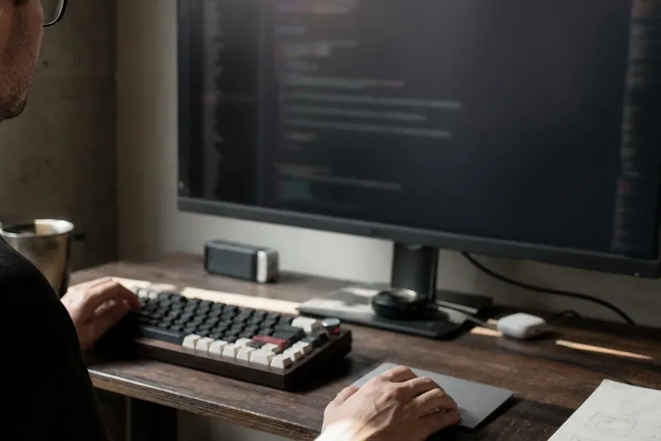 Hands on a keyboard below a monitor with the site code open